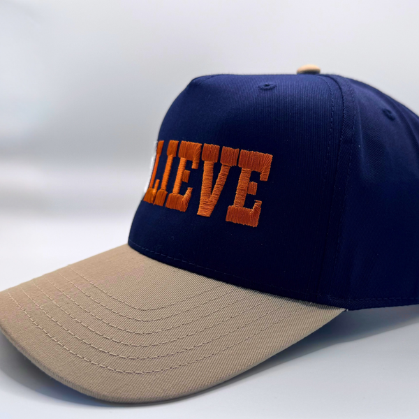 Navy and beige cap with 'BOLIEVE' text on a white background