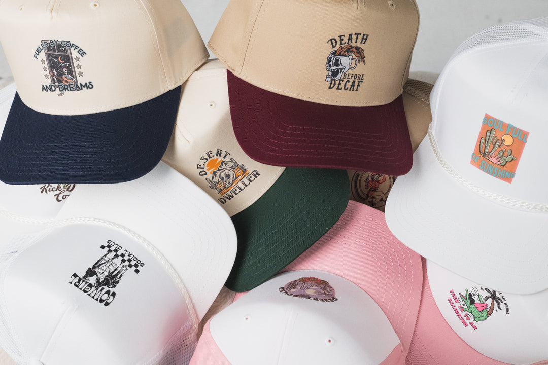 A pile of embroidered hats in cream, navy, pink and burgundy, each one stitched to order by Threaded by Sal