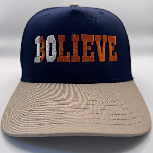 Navy and beige cap with 'BOLIEVE' text on a white background