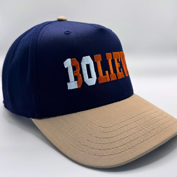 Navy and beige cap with 'BOlieve' embroidered on a white background