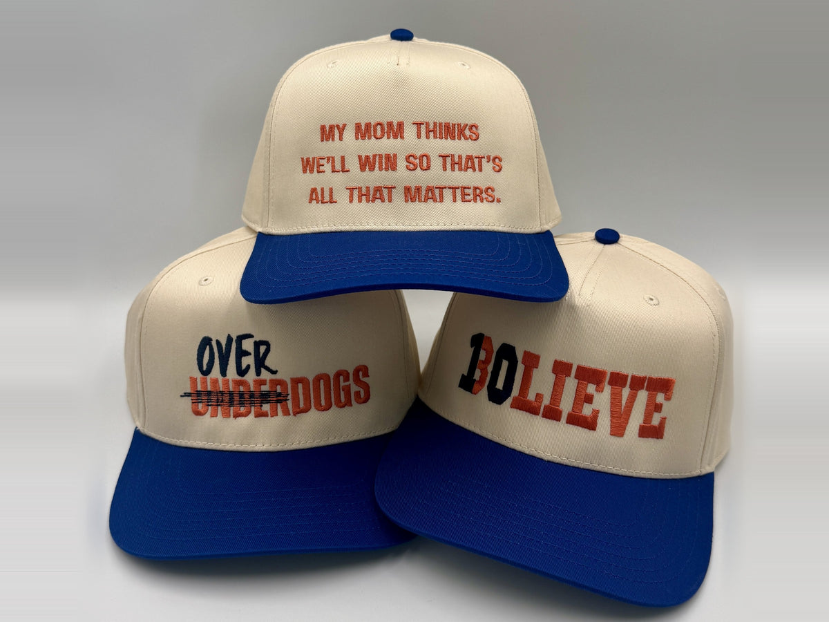 Three embroidered Denver football hats stacked on a seamless: My Mom Thinks We’ll Win, Overdogs, and BOLIEVE, stitched by Threaded by Sal